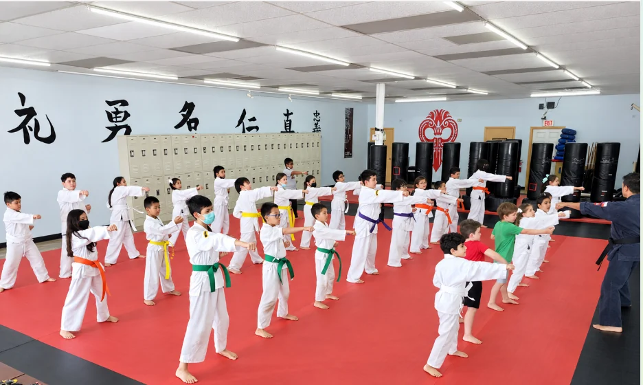 Legacy kids practicing punches together with their instructor in the dojo